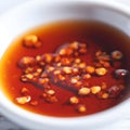Hot sauce of red dry chili peppers with soy oil in a white bowl close-up Royalty Free Stock Photo