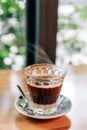 Hot served Vietnamese coffee that can wake you up: Black coffee mix with condense milk in clear glass served on wooden table. Royalty Free Stock Photo