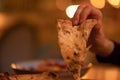 Hot slice of four cheese pizza hanging in hand of woman to eat in an Italian cafe, restaurant in the warm evening light Royalty Free Stock Photo