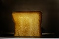 hot slice of toasted white bread in a toaster on a dark background. Horizontal Royalty Free Stock Photo