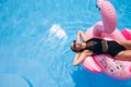 Hot slim woman relaxing on inflatable pink flamingo float mattress in bikini at swimming pool. Attractive fit girl in Royalty Free Stock Photo