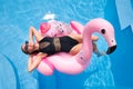 Hot slim woman relaxing on inflatable pink flamingo float mattress in bikini at swimming pool. Attractive fit girl in Royalty Free Stock Photo