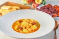 Hot soup sauce with sausages, potatoes and soybeans in the white dish, on the table served also with cheese sticks and sausage Royalty Free Stock Photo