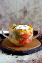 Hot soup with vegetables and meat in a stylish transparent plate on a gray background