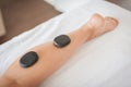 Hot spa volcanic lava stone for massage on woman leg Royalty Free Stock Photo