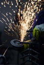 Hot sparks flying while worker is grinding steel pipe with a circular saw.