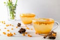 Hot spicy beverage with sea buckthorn in glass cups with fresh raw sea buckthorn berries