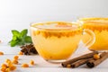 Hot spicy beverage with sea buckthorn in glass cups with fresh raw sea buckthorn berries