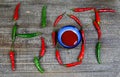 Hot spicy food symbol concept: Close up of blue bowl with chili sauce on wood table with green red Chillies forming the word hot Royalty Free Stock Photo