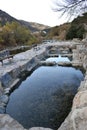 Stone thermal water pools and wooden benches next to the Cidacos river. Royalty Free Stock Photo