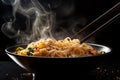 Hot steaming noodles in bow with chopsticks in front of black background