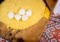 Hot steaming polenta with pieces of cow cheese on a old wooden board on the table