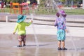 Colorful children dressed in streams of water from the fountain. Hot summer