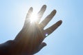 Hot summer sunlight rays pouring through human hand. Hand covering sun light heat temperature. Protection from ultraviolet light