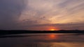 Hot sunset above the forest. Refelctions of red clouds in the water of the lake. bright colors at the end of a summer day