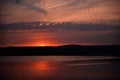 Hot sunset above the forest. Refelctions of red clouds in the water of the lake. bright colors at the end of a summer day Royalty Free Stock Photo