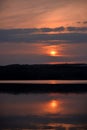 Hot sunset above the forest. Refelctions of red clouds in the water of the lake. bright colors at the end of a summer day