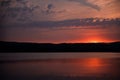 Hot sunset above the forest. Refelctions of red clouds in the water of the lake. bright colors at the end of a summer day Royalty Free Stock Photo