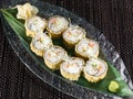 Hot sushi roll with salmon and avocado breading on a glass plate, close up photo on dark background Royalty Free Stock Photo