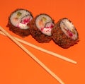 Hot sushi on a stick. Fried sushi. Japanese food on an orange background. Creative serving of the dish