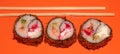 Hot sushi on a stick. Fried sushi. Japanese food on an orange background. Creative serving of the dish