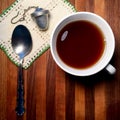 Hot tea on butcher block table with vintage doily and spoon.