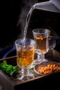 Hot tea flowing in glass cup with berries.