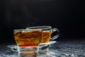 Hot tea in glass cup with steam and lemon, darker background.