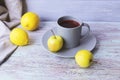 Hot tea in a large cup, lemons and apples on a wooden table, yellow and gray color Royalty Free Stock Photo