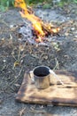 Hot tea in a metal cup with a spoon on a wooden board near the fire. Royalty Free Stock Photo