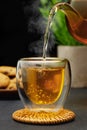 hot tea pouring from teapot into glass cup on table Royalty Free Stock Photo