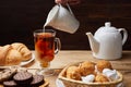 Hot tea put on table, drink breakfast in the morning day, breakfast with croissants, milk and sweets on wooden table Royalty Free Stock Photo