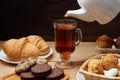 Hot tea put on table, drink breakfast in the morning day, breakfast with croissants and sweets on wooden table Royalty Free Stock Photo