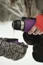 Hot tea in a thermos in hands, in forest. Winter time in Russia