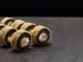 Hot tempura black rice sushi roll with salmon, tuna, rockfish, avocado and cream cheese inside roll on dark background Royalty Free Stock Photo