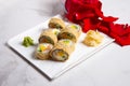 Hot tempura sushi roll with salmon. Red rose petals near served dish on marble background. Breaded Sushi roll portion