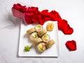 Hot tempura sushi roll with salmon. Red rose petals near served dish on marble background. Breaded Sushi roll portion