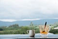 Hot Thai`s style milk tea in a cup with mountain view when a raining is coming from somewhere faraway Royalty Free Stock Photo