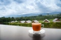 Hot Thai`s style milk tea in a cup with mountain view when a raining is coming from somewhere faraway Royalty Free Stock Photo