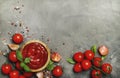 Hot tomato ketchup sauce with garlic, spices and green basil with cherry tomatoes in wooden bowl on gray kitchen table background Royalty Free Stock Photo