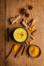 Hot turmeric milk with spices on wooden table