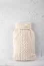 Hot water bottle in a white knitted cover