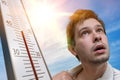 Hot weather concept. Young man is sweating. Thermometer is showing high temperature. Sun in background Royalty Free Stock Photo