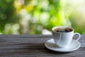 Hot white coffee cup on wooden tabletop on blurred green nature bokeh background Royalty Free Stock Photo