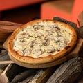 Hot whole pizza on wood with crispy brown crust and filling of chicken fillet and spices. Open fire on blurred