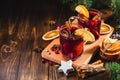 Hot wine drink with spices and fruits in a glass on a wooden board, branches of a Christmas tree and oranges, copy space