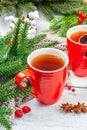 Hot winter or Christmas tea in ceramic red cups. Fir tree branches, lemon slice, spices and berries Royalty Free Stock Photo