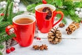 Hot winter or Christmas tea in ceramic red cups. Fir tree branches, lemon slice, spices and berries Royalty Free Stock Photo