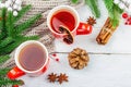 Hot winter or Christmas tea in ceramic red cups. Fir tree branches, lemon slice, spices and berries Royalty Free Stock Photo