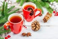 Hot winter or Christmas tea in ceramic red cups. Fir tree branches, lemon slice, spices and berries Royalty Free Stock Photo